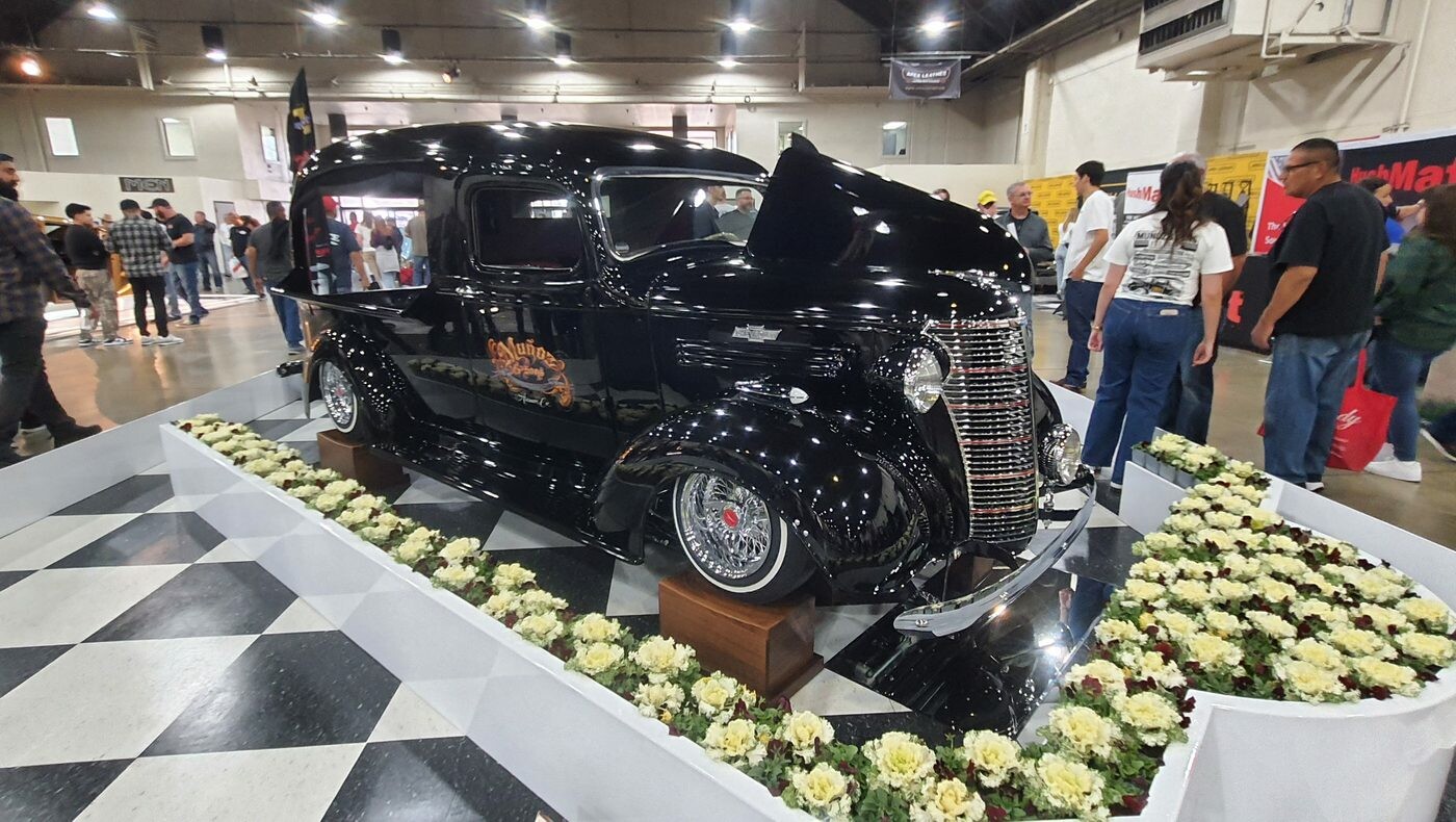 Czarny Chevrolet panel delivery z 1938 roku na szachownicy – przedwojenna furgonetka wśród kwiatów w hali