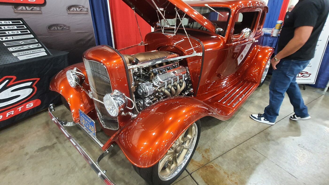 Pomarańczowy Ford 5-window coupe z 1932 roku w candy z chromowanym silnikiem – Deuce na złotych felgach w hali