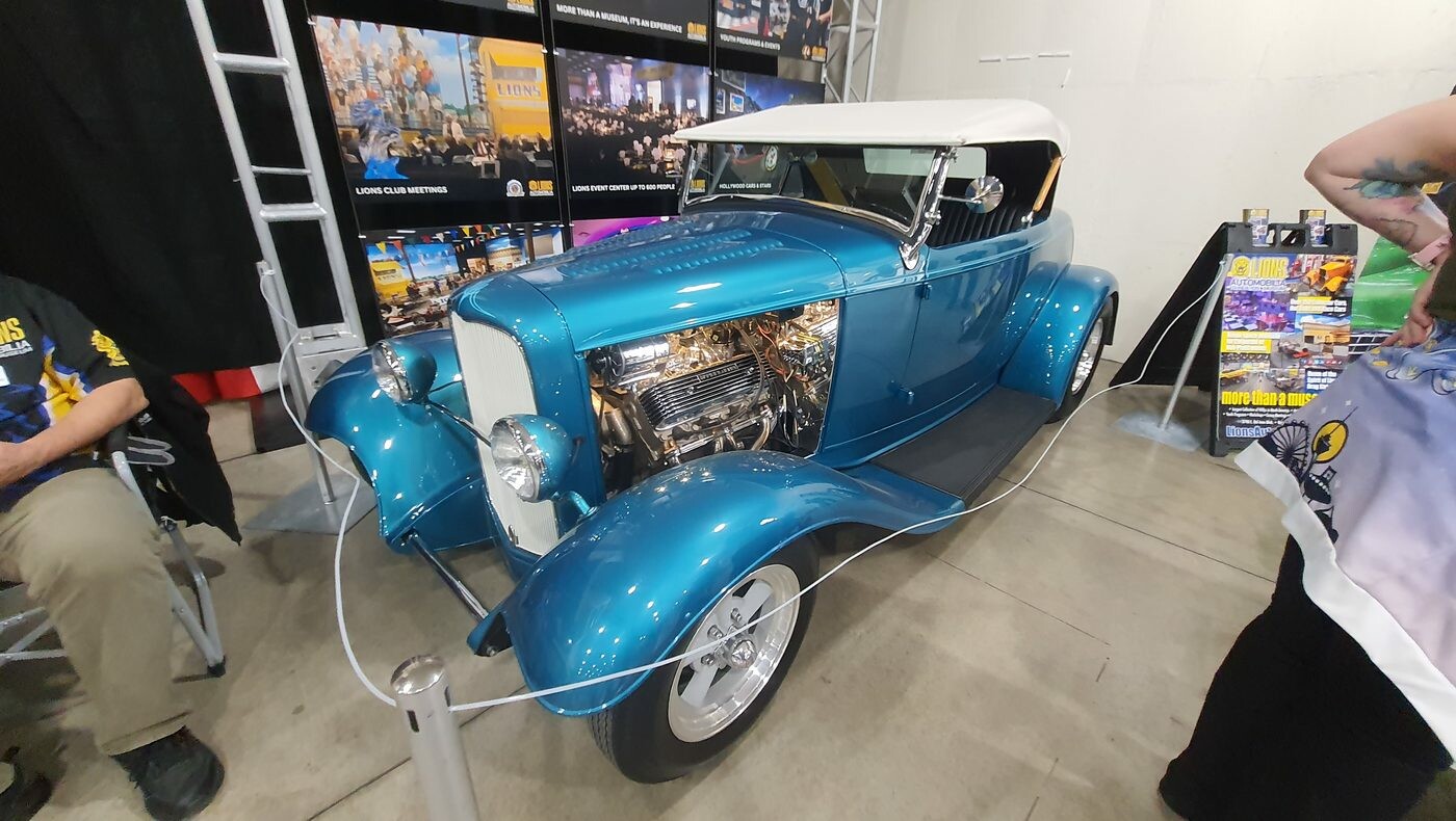 Turkusowy Ford roadster z 1932 roku z białym dachem i chromowanym silnikiem – Deuce na stoisku w hali