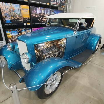 Turkusowy Ford roadster z 1932 roku z białym dachem i chromowanym silnikiem – Deuce na stoisku w hali