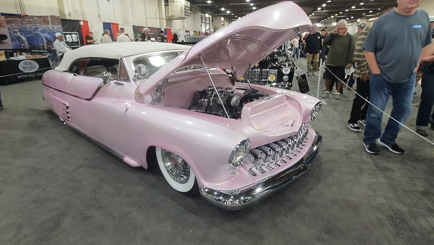 Różowy kustom z lat 50. z zębatą atrapą i białym dachem – obniżony do ziemi, z otwartą maską w hali