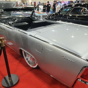 Srebrny Lincoln Continental kabriolet z 1963 roku z otwartym dachem – drzwi „samobójcze” za aksamitnymi sznurami