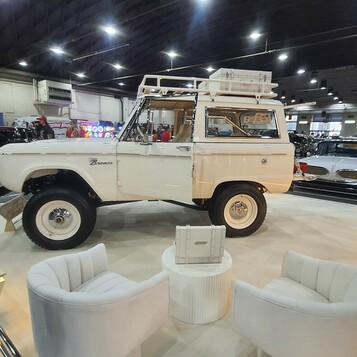 Biały Ford Bronco pierwszej generacji z bagażnikiem dachowym – terenówka na białym stoisku z fotelami