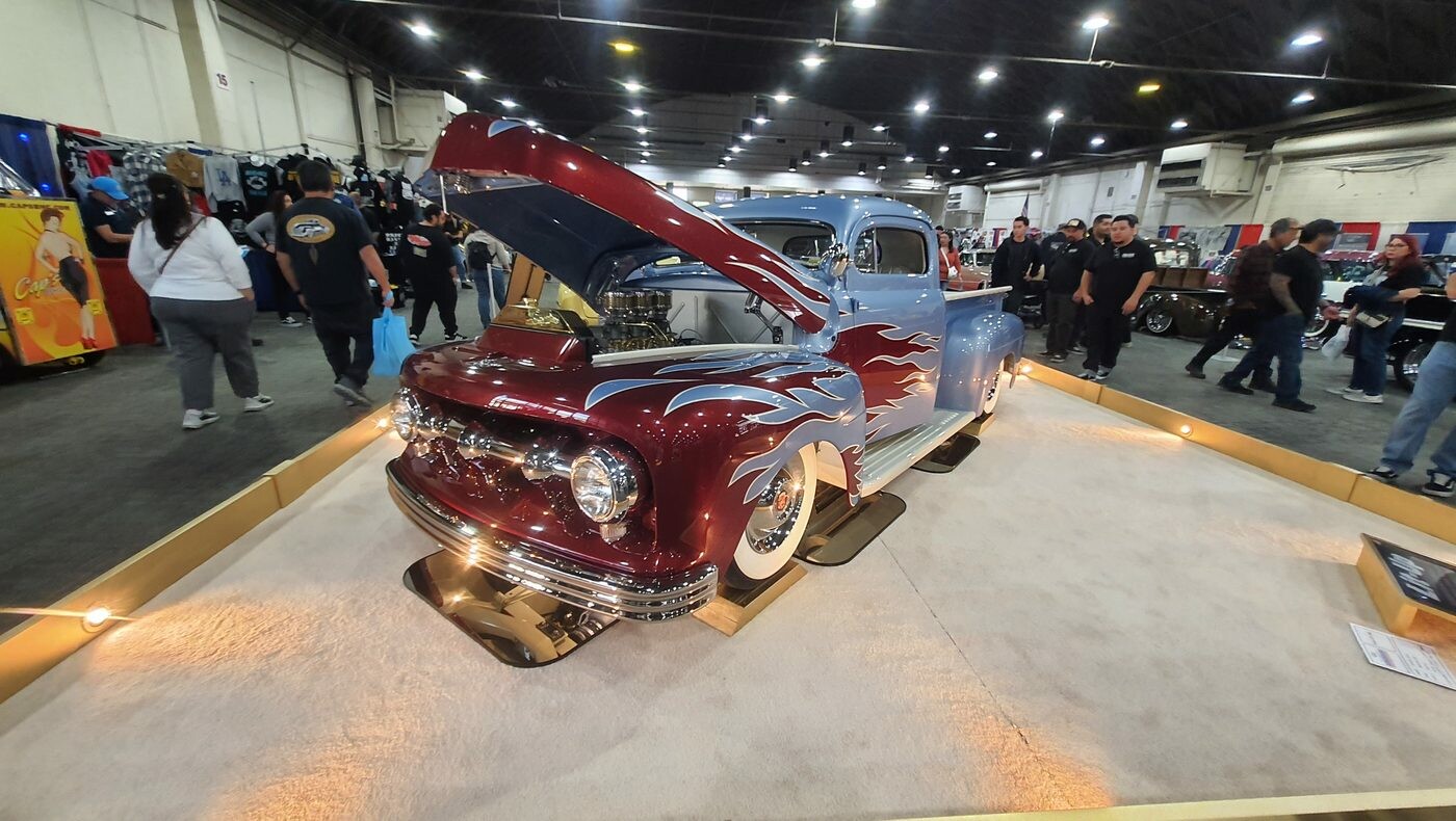 Bordowy Ford F-1 z 1949 roku ze srebrnymi płomieniami – pickup kustom z otwartą maską na podeście w hali