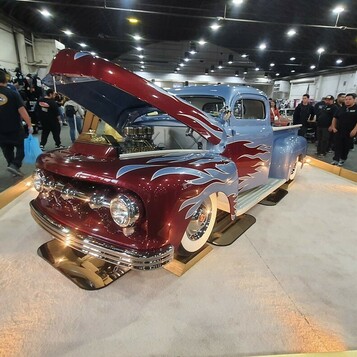 Bordowy Ford F-1 z 1949 roku ze srebrnymi płomieniami – pickup kustom z otwartą maską na podeście w hali