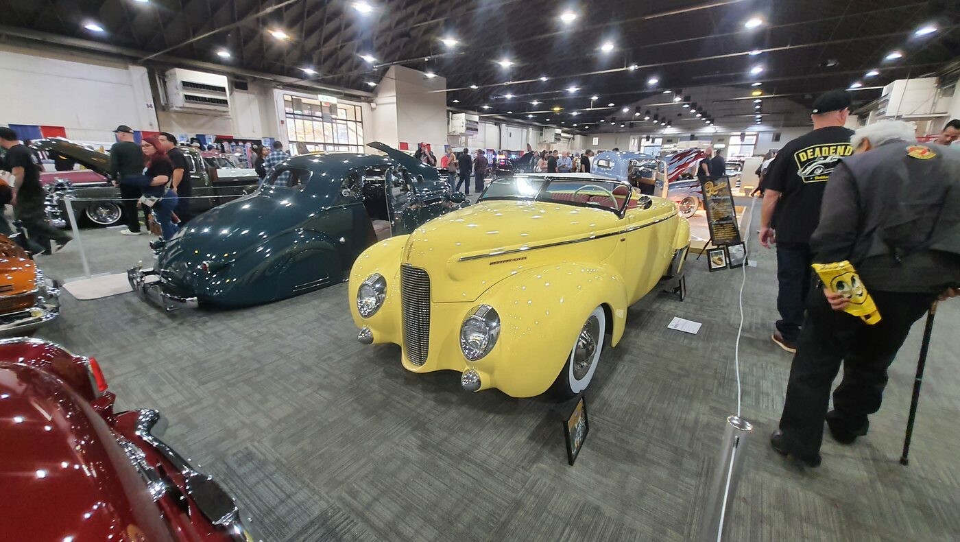 Żółty Ford kabriolet z 1940 roku z opuszczonym dachem – przedwojenny cabriolet z przodu i z tyłu w hali zlotu