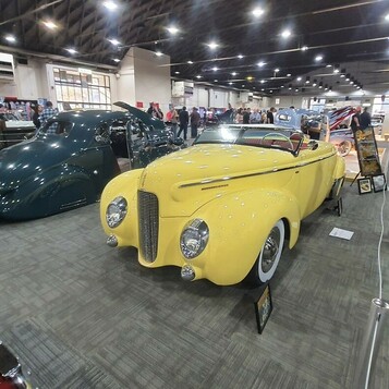 Żółty Ford kabriolet z 1940 roku z opuszczonym dachem – przedwojenny cabriolet z przodu i z tyłu w hali zlotu