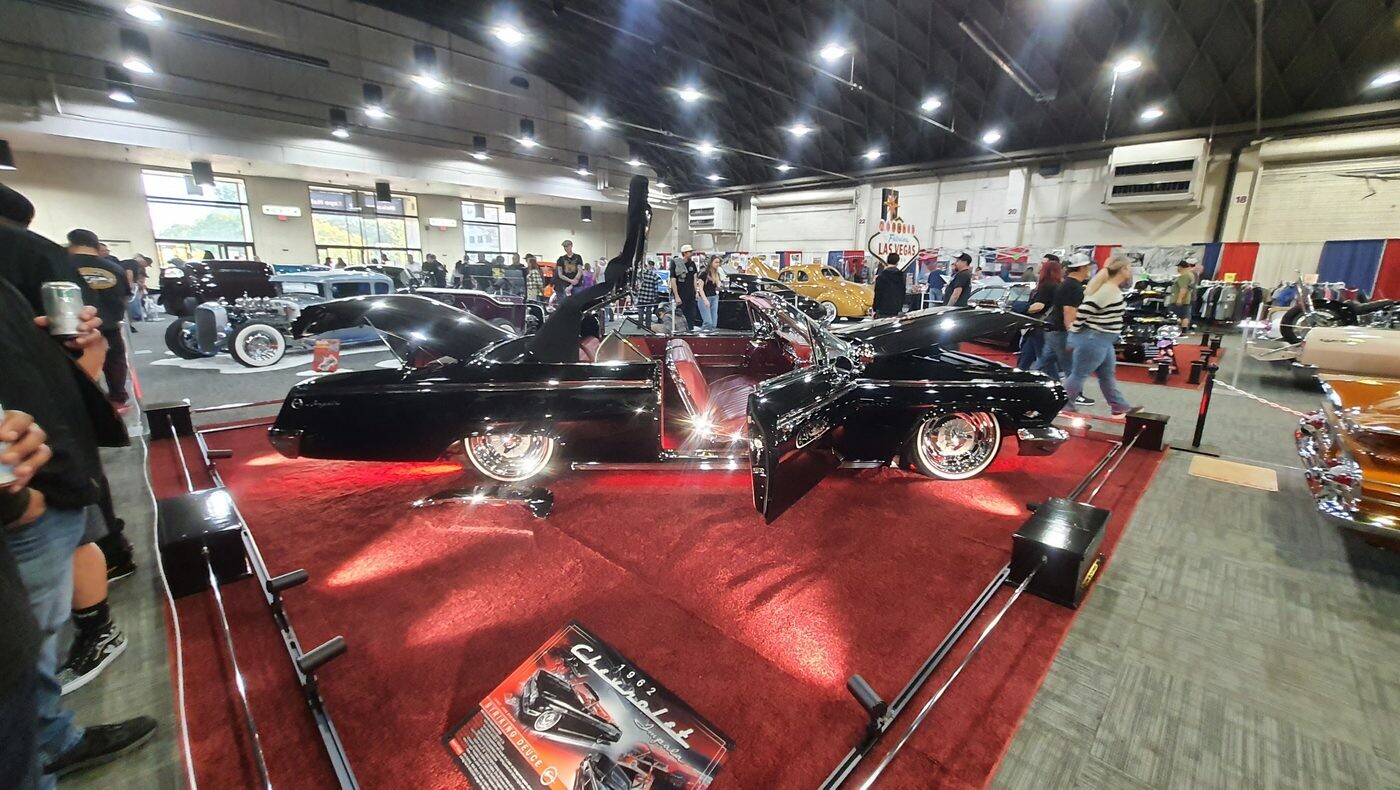 Czarny chopped kustom z otwartą maską na czerwonym dywanie – lead sled na stoisku w hali
