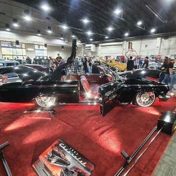 Czarny chopped kustom z otwartą maską na czerwonym dywanie – lead sled na stoisku w hali