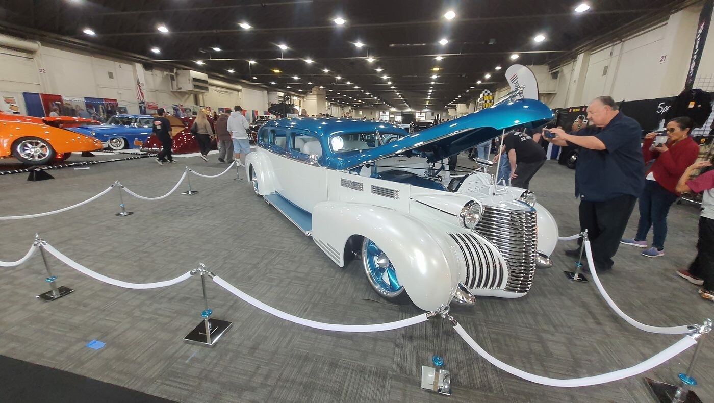 Perłowo-biała limuzyna Cadillac z 1940 roku z turkusowym dachem – kustom z otwartą maską za sznurami w hali