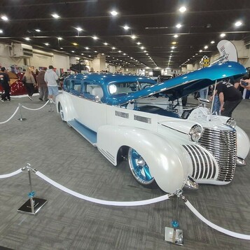 Perłowo-biała limuzyna Cadillac z 1940 roku z turkusowym dachem – kustom z otwartą maską za sznurami w hali