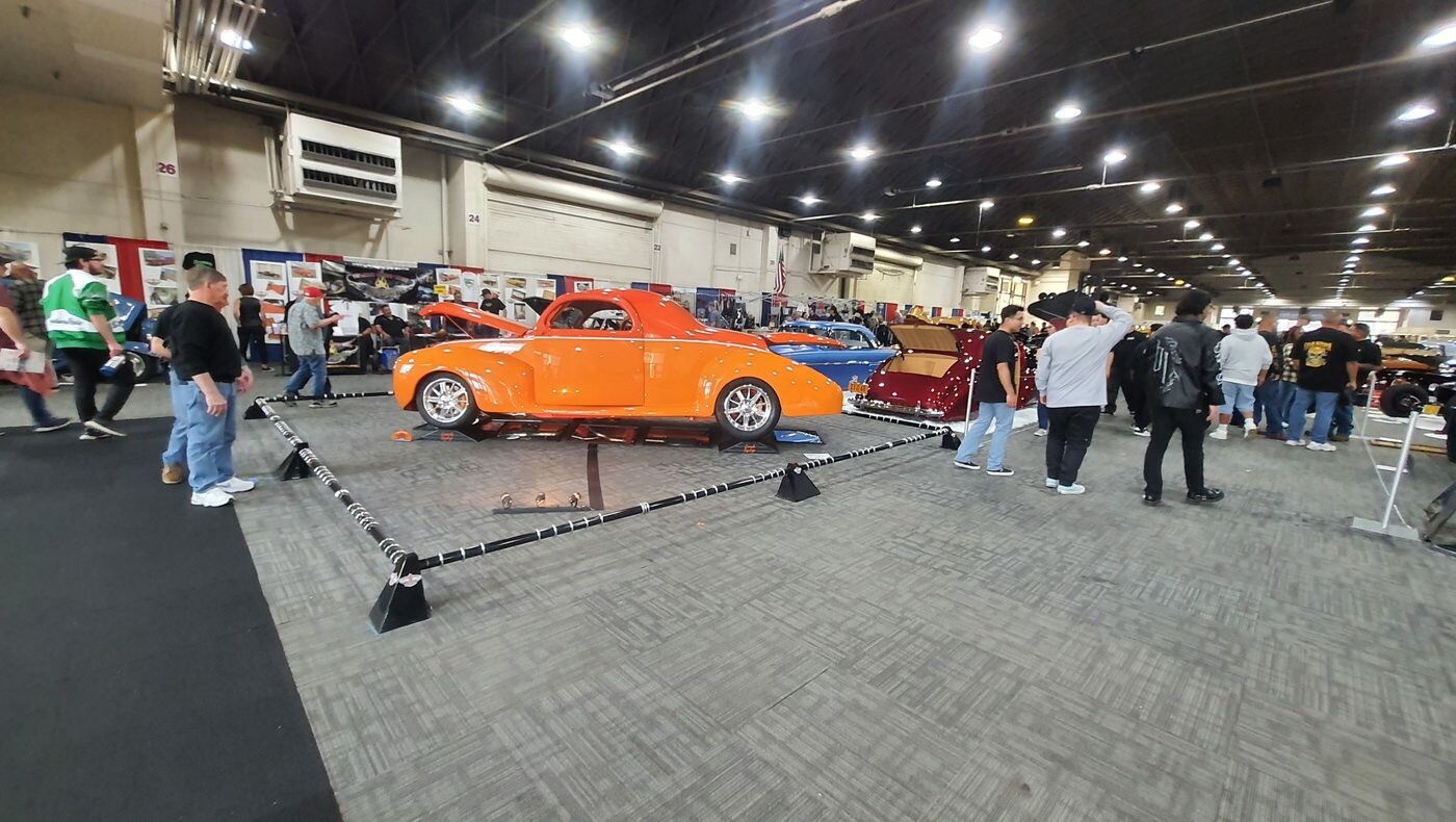 Pomarańczowy Willys coupe z 1941 roku street rod – z przodu i z tyłu za sznurem w hali zlotu