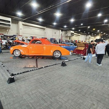 Pomarańczowy Willys coupe z 1941 roku street rod – z przodu i z tyłu za sznurem w hali zlotu