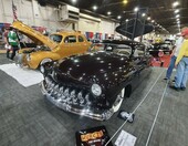 Śliwkowy Mercury z 1951 roku chopped z zębatą atrapą – lead sled na białym „śniegu” z otwartą maską w hali – zdjęcie 1