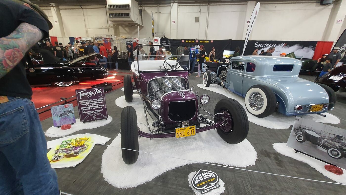 Fioletowy Ford Model T roadster z 1927 roku na drucianych kołach – tradycyjny hot rod na białym podłożu w hali