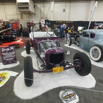 Fioletowy Ford Model T roadster z 1927 roku na drucianych kołach – tradycyjny hot rod na białym podłożu w hali
