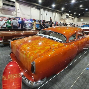 Pomarańczowy Chevrolet Bel Air z 1954 roku chopped w płomieniach – kustom candy na hali zlotu