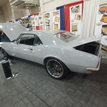 Szary Pontiac Firebird z 1967 roku pro touring na stoisku tapicera – otwarta maska i bagażnik w hali
