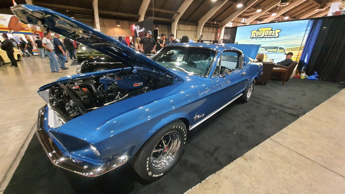Niebieski Ford Mustang fastback z 1968 roku z otwartą maską – Acapulco Blue na stoisku w hali zlotu