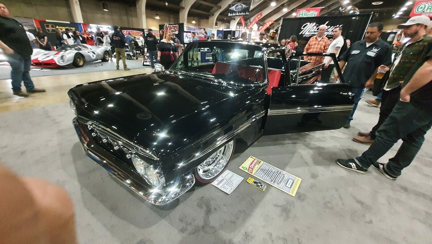 Czarny Chevrolet C10 z 1970 roku z czerwonym wnętrzem – pickup z otwartymi drzwiami na stoisku w głównej hali