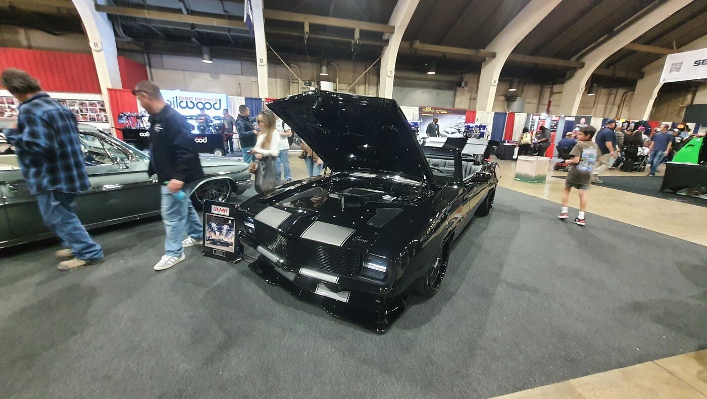 Czarny Chevrolet Camaro kabriolet z 1969 roku ze srebrnymi pasami – pro touring z otwartą maską w hali