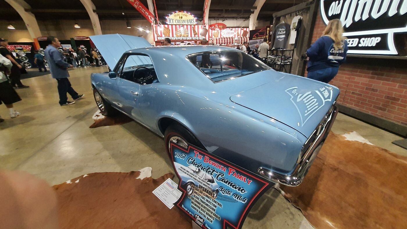 Błękitny Chevrolet Camaro z 1967 roku z otwartą maską – pierwszy rocznik Camaro od tyłu w głównej hali