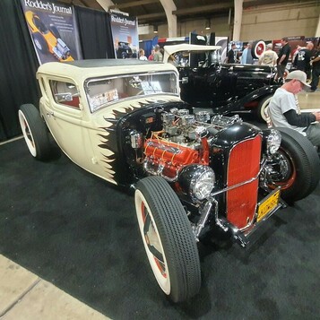 Biały Ford Model A coupe z czerwonymi felgami i czerwonym silnikiem – tradycyjny hot rod na stoisku Rodder's Journal