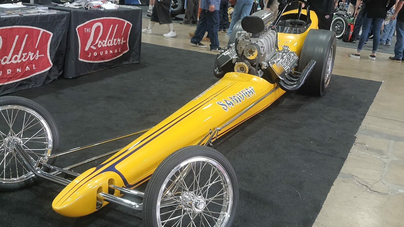 Żółty dragster slingshot z kompresorem – klasyczna wyścigówka na ćwierć mili na stoisku Rodder's Journal