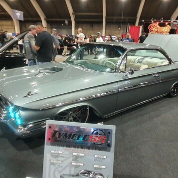Srebrnozielony Chevrolet Impala z 1961 roku z otwartą maską – „bubble top” pro touring na dużych felgach w hali