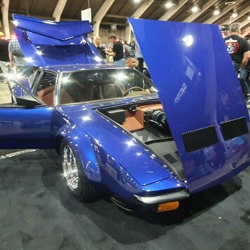 Niebieska De Tomaso Pantera z otwartymi wszystkimi klapami – włoskie nadwozie, V8 Forda i brązowe wnętrze w hali