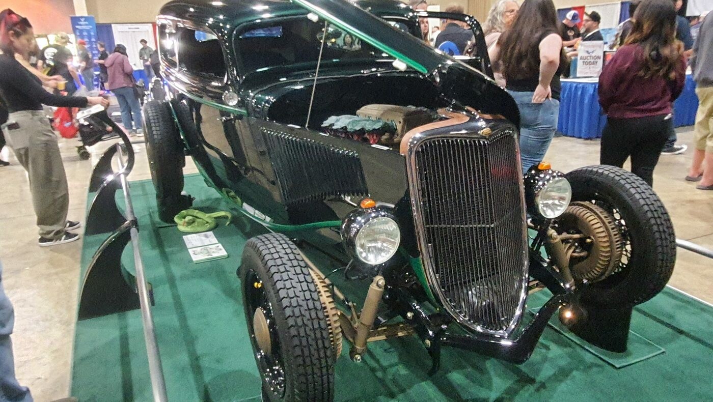 Czarny Ford Tudor sedan z 1934 roku bez maski – hot rod highboy z zielonymi akcentami na zielonym dywanie