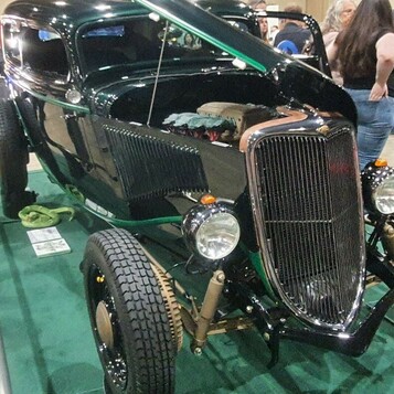Czarny Ford Tudor sedan z 1934 roku bez maski – hot rod highboy z zielonymi akcentami na zielonym dywanie
